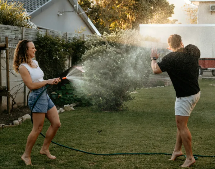 Leane spraying Anru with a garden hose on the lawn